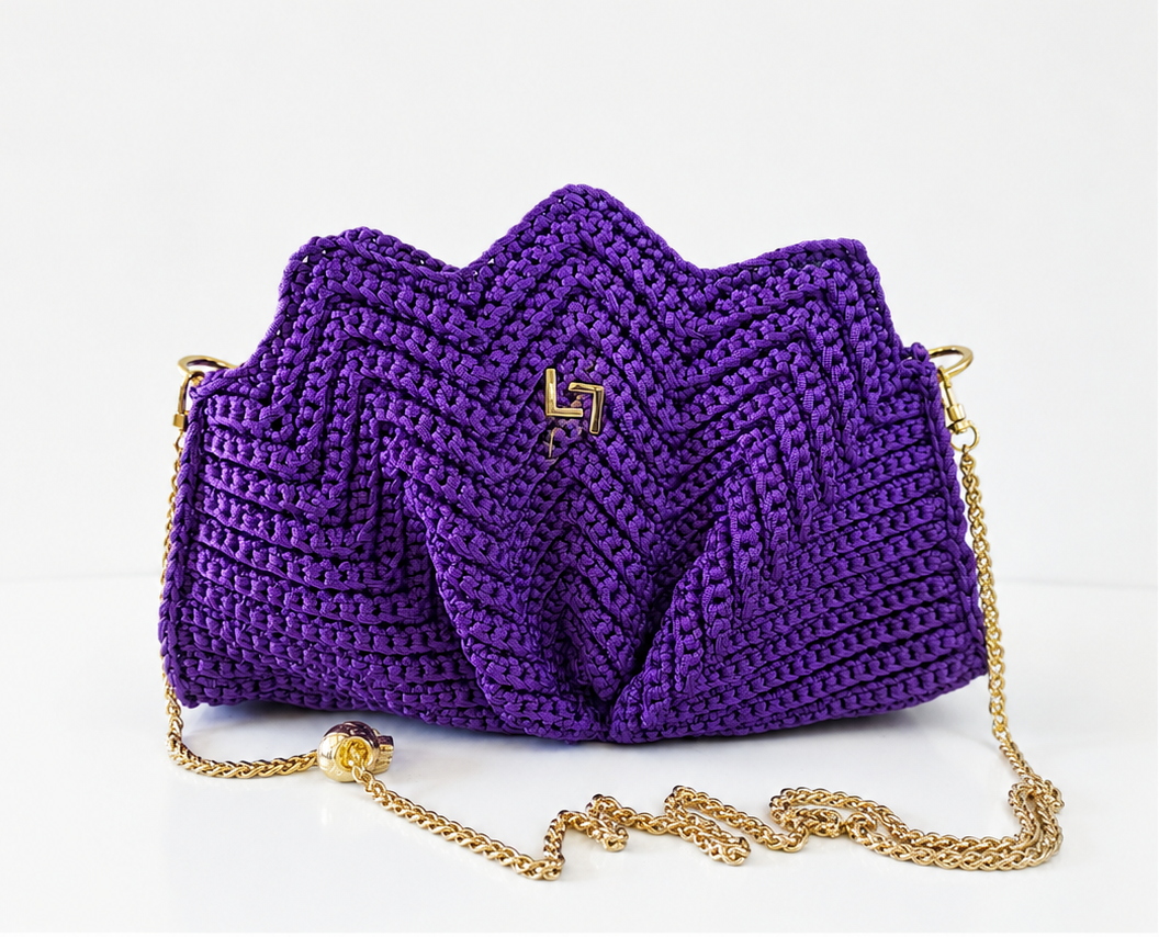 Purple crocheted handbag with a gold chain on a white background