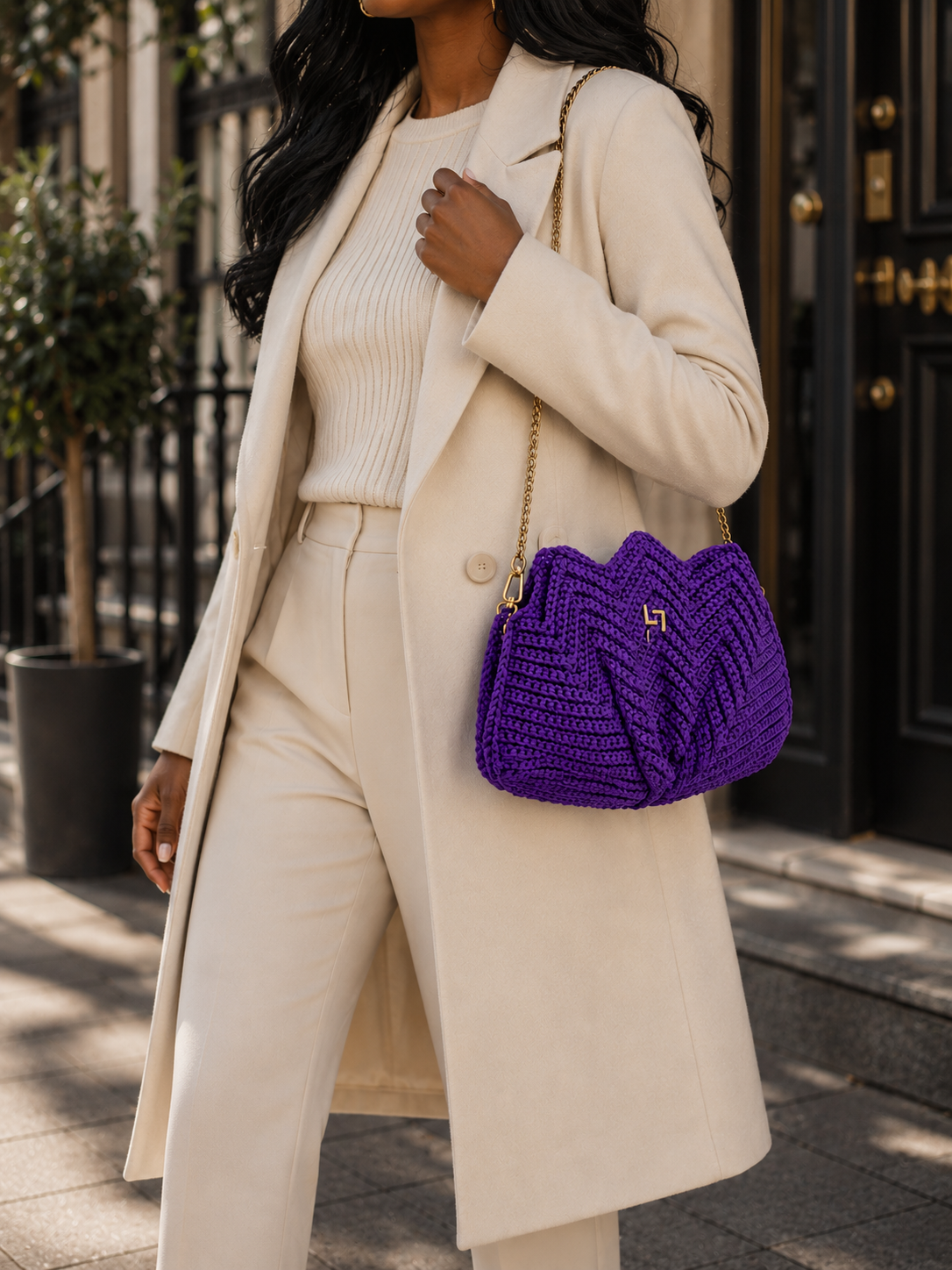 Handmade crochet statement handbag with sculptural pleated design, adjustable gold chain strap, and gold-tone hardware.
