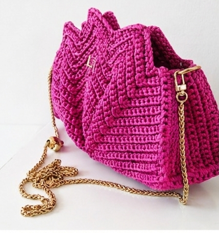 Pink crochet bag with a gold chain on a white background