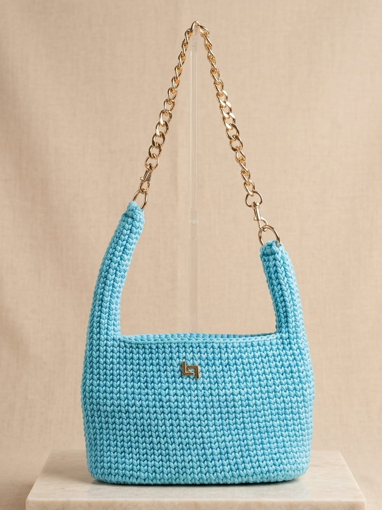 Blue crochet handbag with a gold chain on a beige background