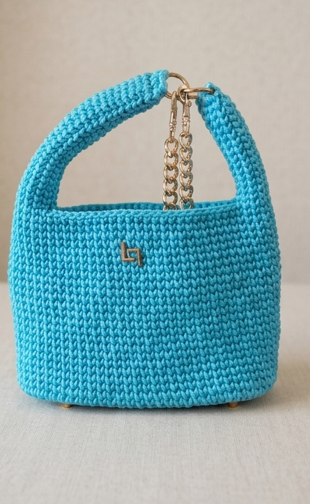 Blue knitted handbag with a gold chain handle on a light gray background